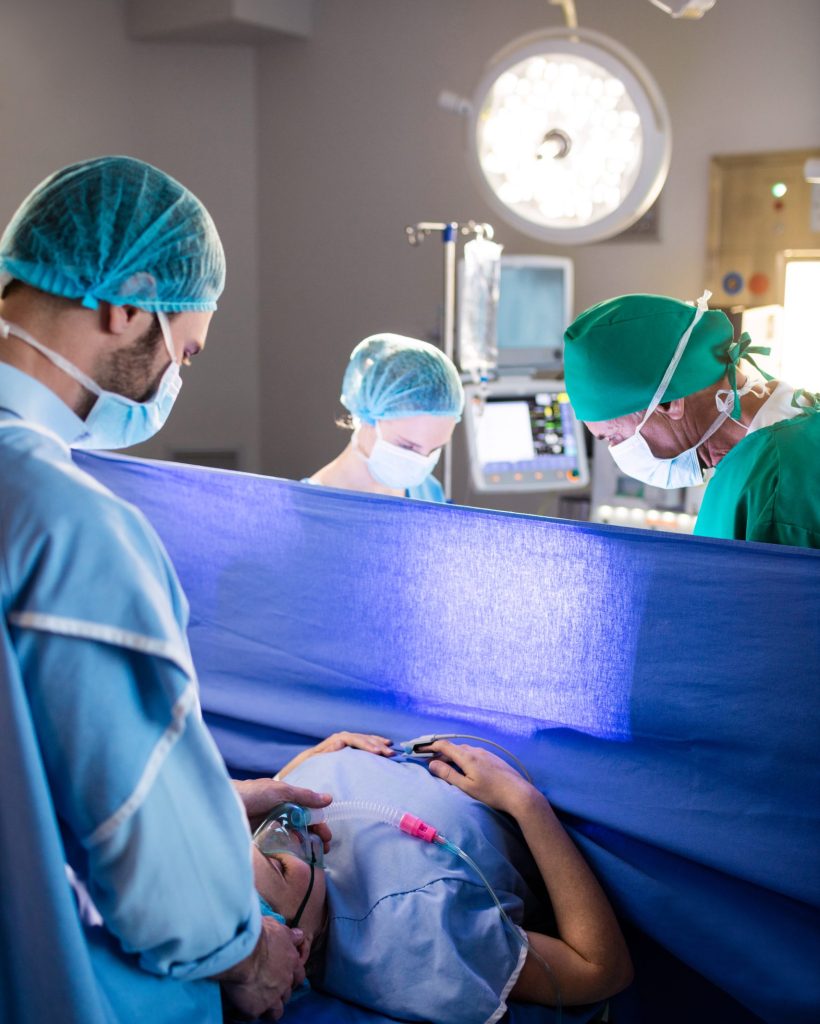 Doctor examining pregnant woman during delivery in operating room